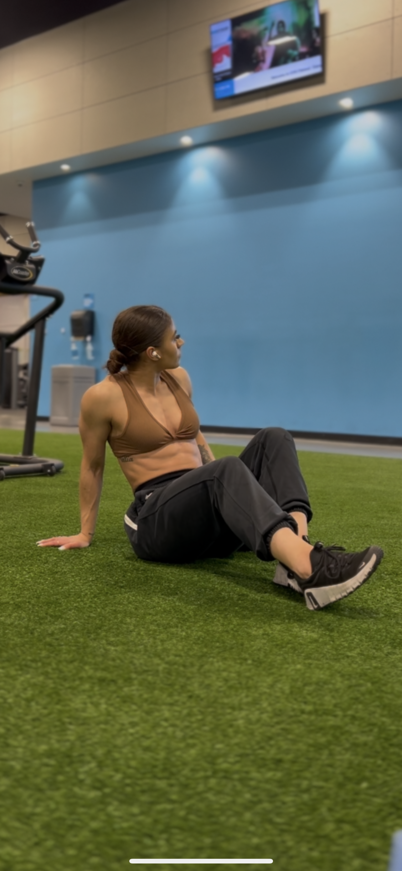 Woman sitting on a green floor in a gym setting